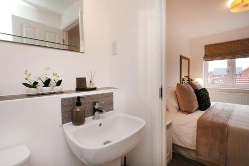 a white bathroom with a sink and a bed at Jasmine House in Nottingham