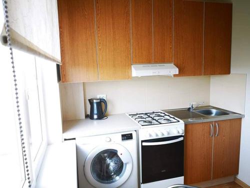 a small kitchen with a stove and a washing machine at Trumpalaikė buto nuoma Plungėje in Plungė