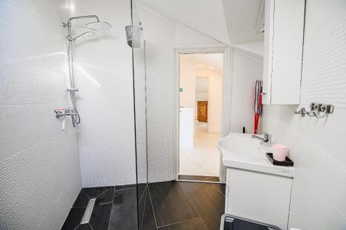 a white bathroom with a shower and a sink at Apartments Rosana in Umag