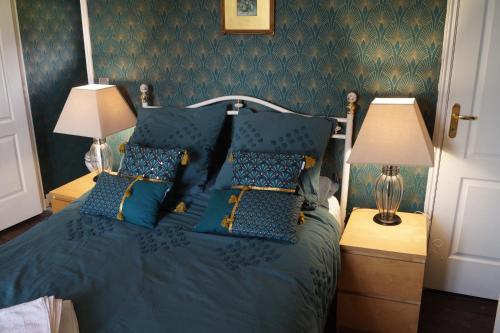 a bedroom with a blue bed with blue pillows at Maison Des Glycines in Droux