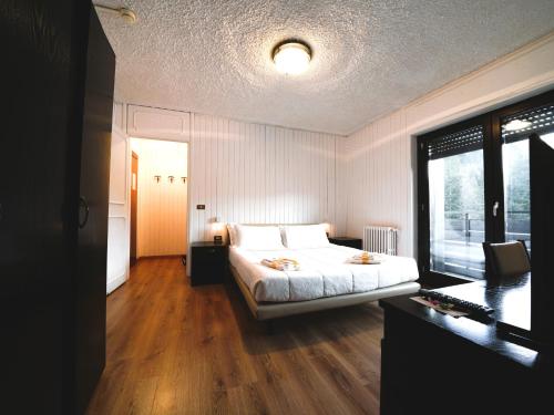 a bedroom with a bed and a large window at Hotel Arlecchino - Dada Hotels in Madesimo