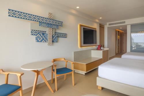 a bedroom with a bed and a table and chairs at Royalton Splash Riviera Cancun, An Autograph Collection All-Inclusive Resort in Cancún