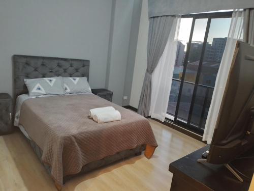 um quarto com uma cama e uma televisão de ecrã plano em Departamento acogedor y moderno em Cochabamba