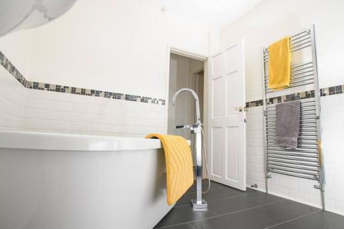 a bathroom with a white tub and a yellow towel at Close to castle + Parking for 4 Cars in Lincolnshire