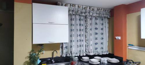uma cozinha com um lavatório e uma janela com uma cortina em C & B APARTAMENTOS em Jauja