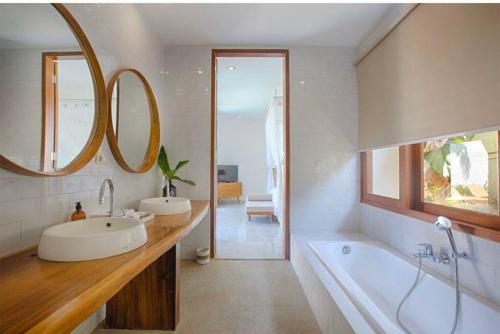 uma casa de banho com 2 lavatórios, uma banheira e um espelho. em New stylish private villa with 2 bedrooms villa in Canggu em Tumbak Bayuh