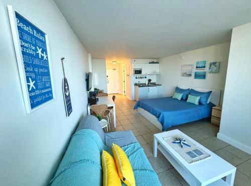 a living room with a blue couch and a table at Daytona Beach Club Studios! in Daytona Beach