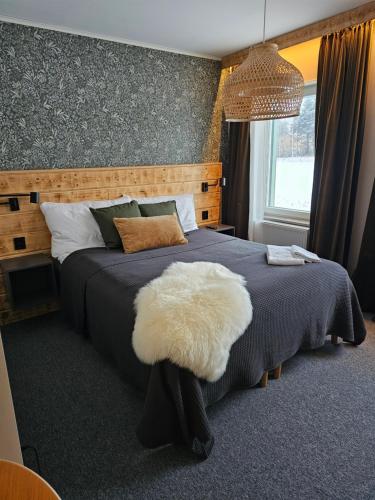 a bedroom with a large bed with a white furry chair at Hotellet i Jörn AB in Jörn