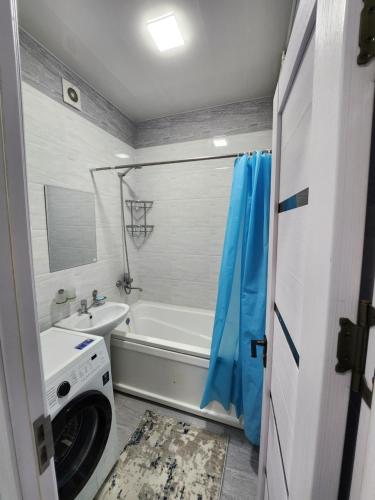 een badkamer met een bad, een wastafel en een wasmachine bij Улица Мирзо Улугбек дом 75, кв 125 in Yalanghoch