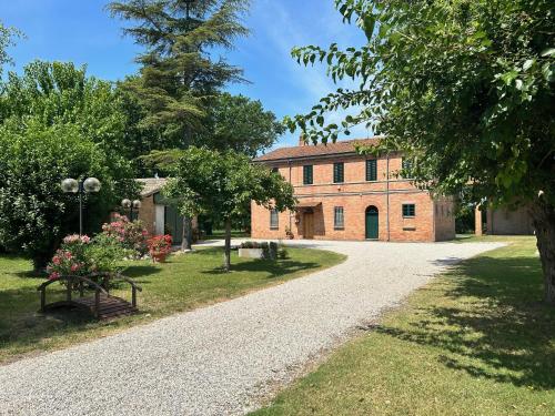 une allée menant à un grand bâtiment en briques dans l'établissement La casa delle Querce, à San Pietro in Vincoli