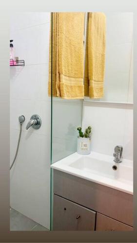 a bathroom with a sink and a shower with a yellow towel at Riana in Tel Aviv