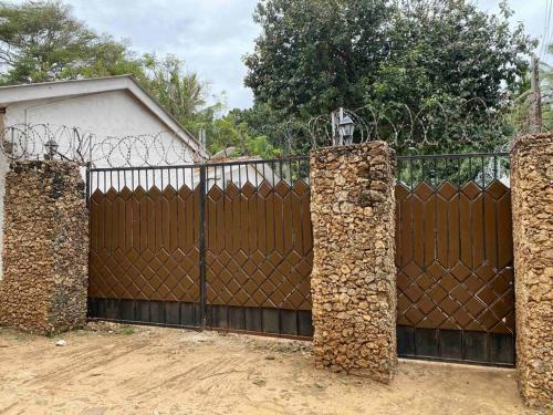a wooden fence with a gate with stone pillars at Cynthia’s Homestays@0723632635 in Malindi