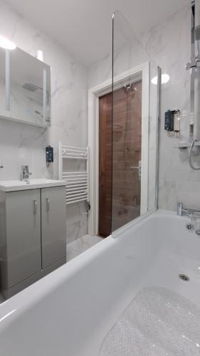 baño blanco con ducha y lavamanos en AT Evita Suites, en Cardiff