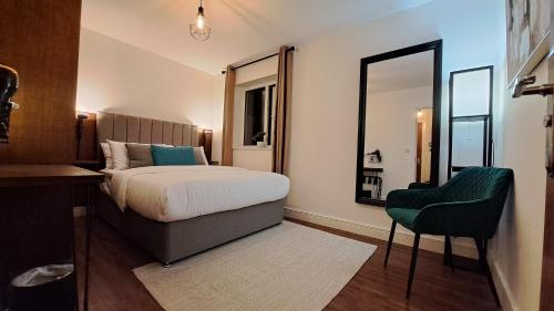 AT Evita Suites في كارديف: غرفة نوم بسرير وكرسي ومرآة