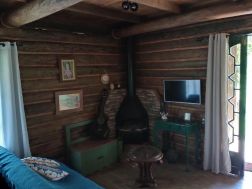 a living room with a fireplace and a television at Chalé de Toras in Campo Alegre