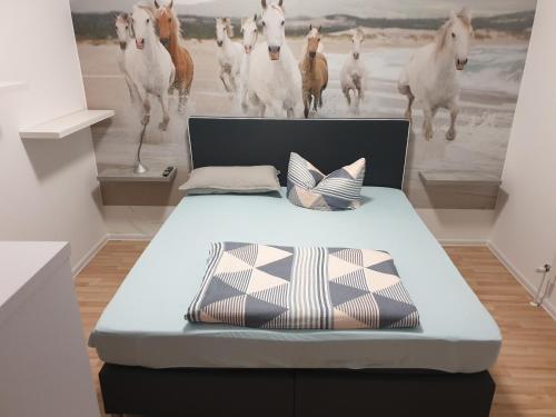 a bed in a room with a painting of horses at City Pension Spremberg in Spremberg