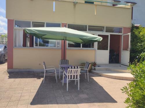 uma mesa com cadeiras e um guarda-sol em frente a um edifício em Villa Crescenza em Mola di Bari