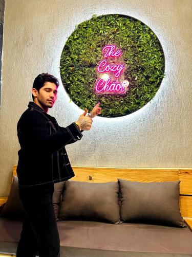 a man standing next to a couch with a sign at The Cozy Chaos in Agra