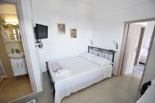 een witte slaapkamer met een bed en een wastafel bij House with view sound of waves in Paránimfoi
