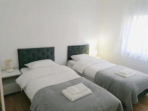 2 bedden in een slaapkamer met witte lakens en handdoeken bij Apartman STAR in Široki Brijeg