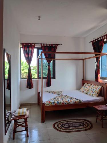 a bedroom with a canopy bed and two windows at STUX HOMES in Mombasa