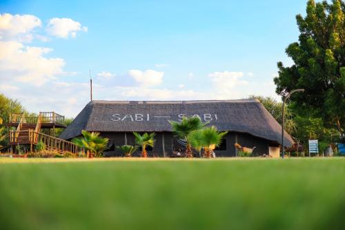a building with a thatch roof with the word sail bali on it at SABI Escapes in Mochudi