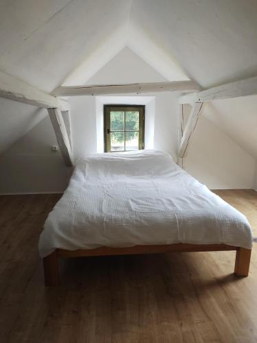Chronowska chatka - zabytkowy dom z bali : سرير كبير في غرفة مع نافذة