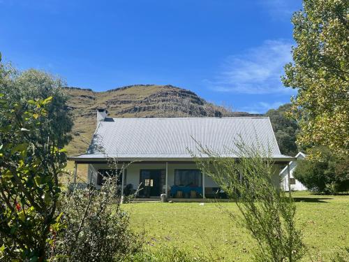 a white house with a mountain in the background at Bamboo Mountain Farm in Underberg