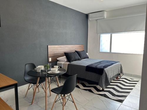 een slaapkamer met een bed en een tafel en stoelen bij Vidrio Suites Col Americana in Guadalajara