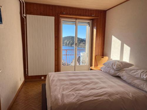 a bedroom with a bed and a large window at App 2-3 p Lake View Vallée de Joux in Le Pont