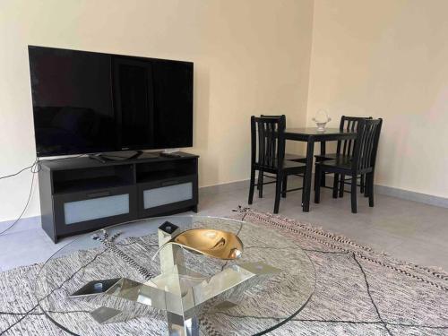 a living room with a television and a table with chairs at Superbe appartement proche de toutes les commodité in Rabat