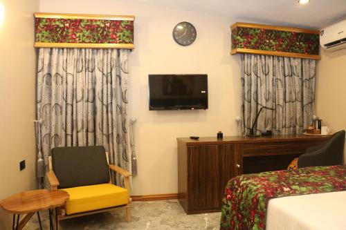 a room with a bed and a desk and a tv at Saire Hotels Ibadan in Ibadan