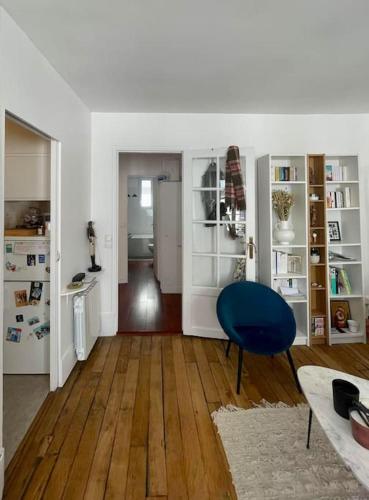 ein Wohnzimmer mit einem blauen Stuhl und Holzböden in der Unterkunft Appartement proche Arc Triomphe / Champs Elysées in Paris