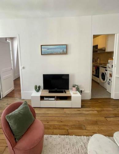 ein Wohnzimmer mit einem TV und einem Stuhl in der Unterkunft Appartement proche Arc Triomphe / Champs Elysées in Paris
