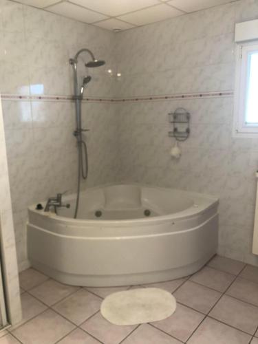 La salle de bains est pourvue d'une baignoire blanche et d'une douche. dans l'établissement Les oiseaux Mimizan Plage, à Mimizan