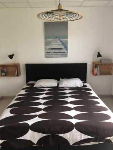une chambre avec un lit avec une couette noire et blanche dans l'établissement Les oiseaux Mimizan Plage, à Mimizan