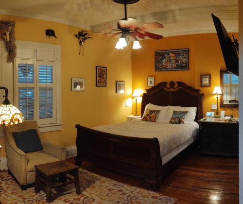 a bedroom with a bed and a chair and a ceiling fan at The Blue60 Marigny Inn in New Orleans