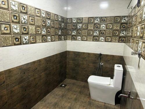 a bathroom with a toilet and a wall with tiles at Thachees heritage stay in Varkala