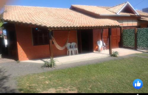 uma casa com um alpendre com duas cadeiras e uma rede de descanso em Casa da Felicidade em Tramandaí