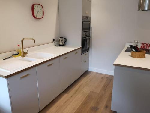 a kitchen with white cabinets and a clock on the wall at Owl's Hoot in Snettisham