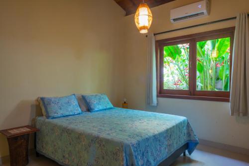 a bedroom with a bed with blue sheets and a window at Quintal de Barros in Arraial d'Ajuda