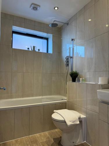 a bathroom with a toilet and a tub and a sink at Spacious 2BR with balcony in Brentwood in Brentwood