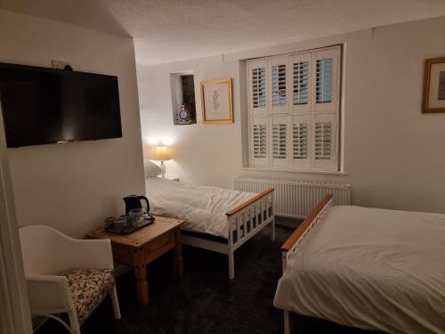 a hotel room with two beds and a desk and a tv at Poppy Cottage in Whitby