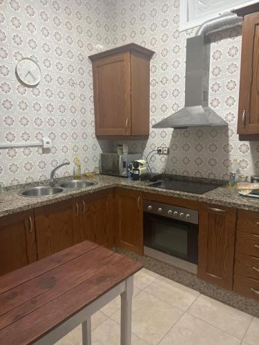 cocina con armarios de madera, fregadero y fogones en Habitaciónes La JUNGLA 22, en Algeciras