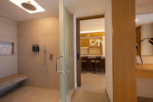 a bathroom with a walk in shower and a dining room at Royalton Splash Riviera Cancun, An Autograph Collection All-Inclusive Resort in Cancún