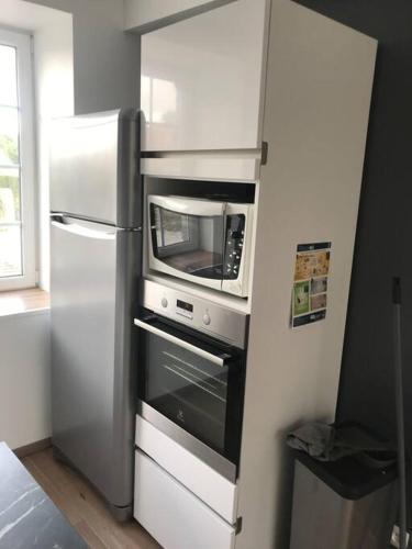 une cuisine avec un réfrigérateur et un micro-ondes dans l'établissement Maison familiale dans le Cotentin, à Virandeville