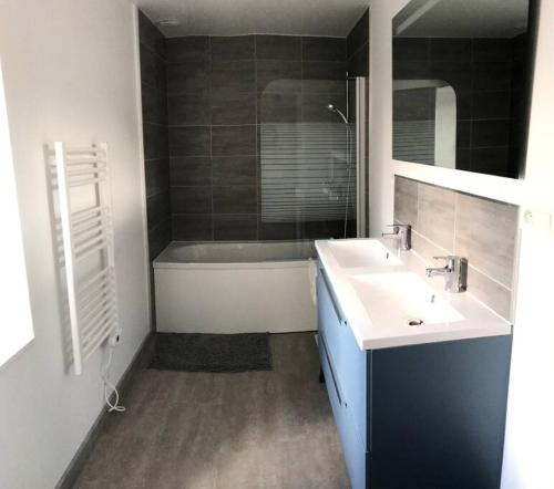 une salle de bain avec deux lavabos et une baignoire dans l'établissement Maison familiale dans le Cotentin, à Virandeville