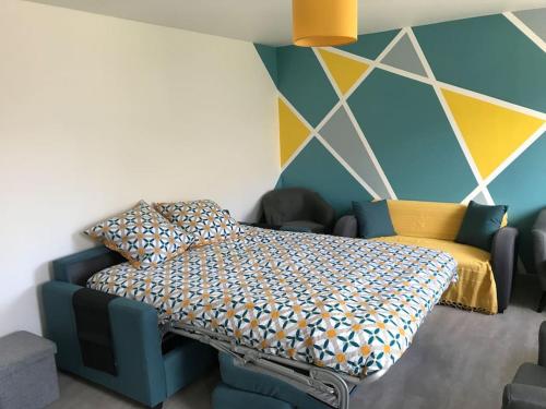 - une chambre avec un lit et un mur coloré dans l'établissement Maison familiale dans le Cotentin, à Virandeville