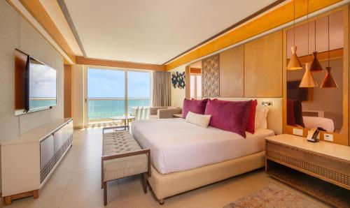 a bedroom with a bed and a television and a desk at Royalton Splash Riviera Cancun, An Autograph Collection All-Inclusive Resort in Cancún