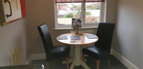 a wooden table with two chairs and a window at Felpham Guest House - Self Catering in Bognor Regis